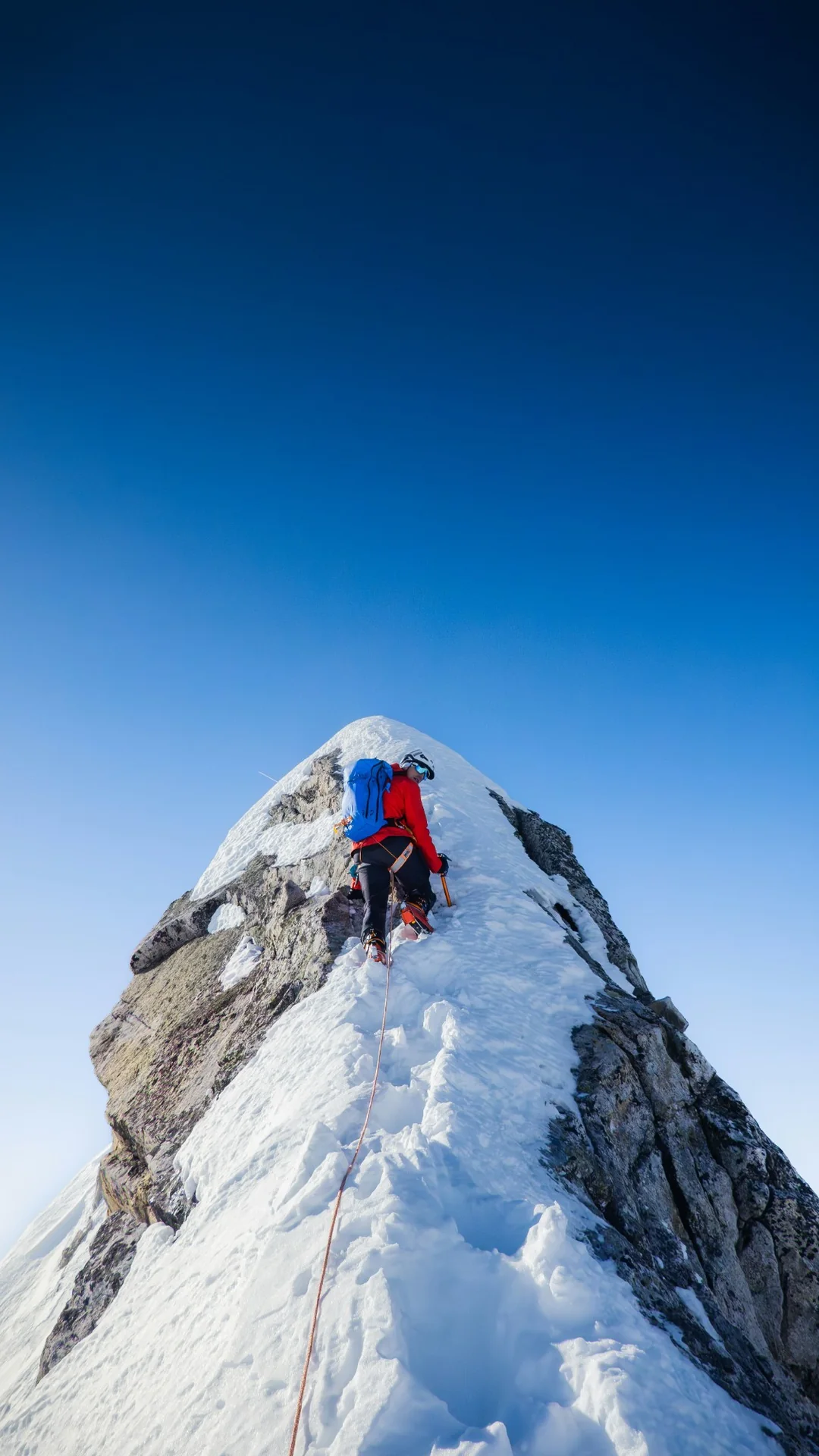 A mountain athlete scrambling over a boulder field high on a ridge