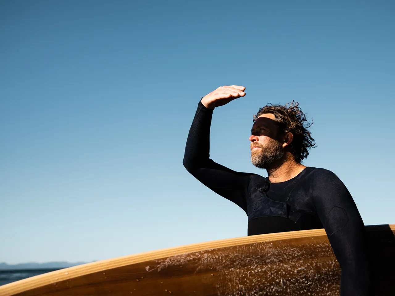 Guy with surfboard looking out at ocean